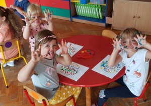Dzieci pokazują brudne od farby rączki