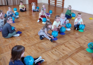 Dzieci siedzą po turecku z piłkami