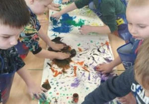 Chłopcy wspólnie malują z wykorzystaniem farb w różnych kolorach