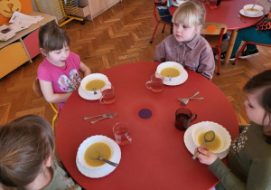 Dziewczynki siedzą przy stole z zupą brokułową