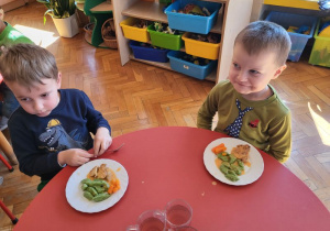 Chłopcy jedzą kopytka szpinakowe z marchewką i mięskiem