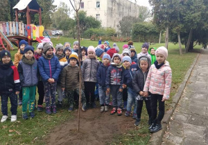 Dzieci stoją przy wsadzonym drzewie