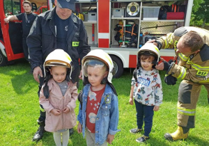 Dzieci mierzą chełmy strażackie