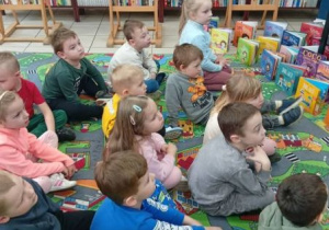 Przedszkolaki słuchają bajki czytanej przez bibliotekarkę